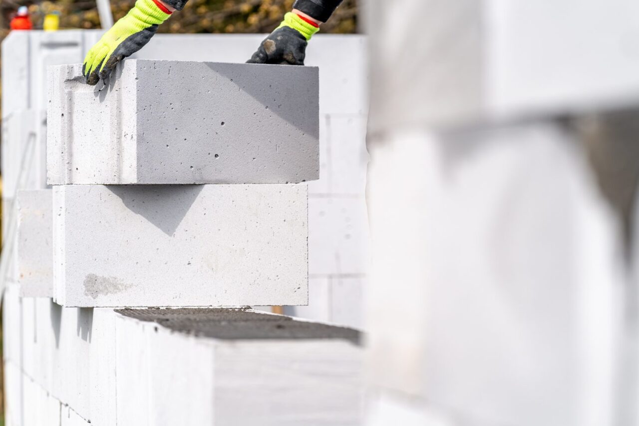 Un professionnel applique de l’enduit sur un mur en parpaing à l’aide d’une taloche.